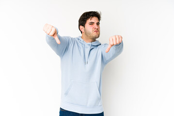 Young man isolated on white background showing thumb down and expressing dislike.