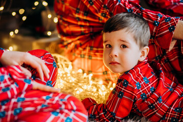 Happy family getting ready for Christmas. Father, mother and little son in red plaid pajamas at home.