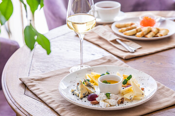 cheese platter. A plate with a variety of cheeses. Snacks. Glass of wine with cheese.