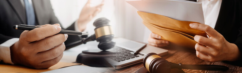 Business and lawyers discussing contract papers with brass scale on desk in office. Law, legal services, advice, justice and law concept picture with film grain effect