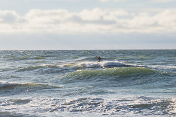 Professional kite surfer kite boarder rides the waves in the open sea, with a water splash, kitesurfing, kiteboarding extreme fun water sport in the summer sunny day