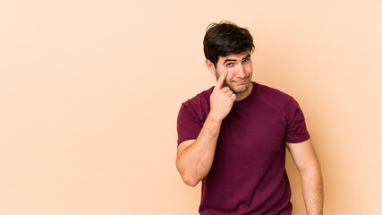 Young man isolated on beige background crying, unhappy with something, agony and confusion concept.