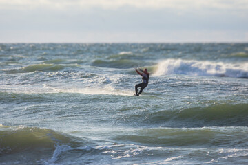 Professional kite surfer kite boarder rides the waves in the open sea, with a water splash, kitesurfing, kiteboarding extreme fun water sport in the summer sunny day