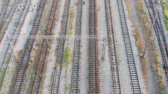 Empty parallel railway tracks in a train station. Rails, ties and ballast of a permanent way. Aerial top view.