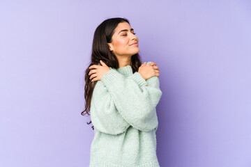 Young indian woman isolated on purple background hugs, smiling carefree and happy.