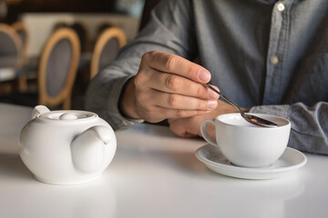 
The guy is drinking tea while sitting in a cafe