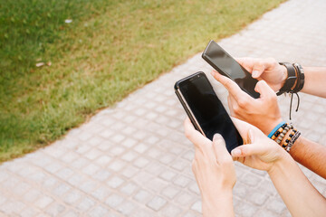 A couple's hands holding their cell phones in the street.