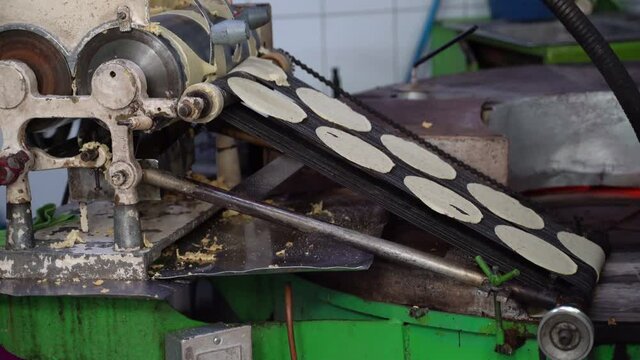 Tortillas stamped out into perfect circles move down a conveyor belt towards the oven where they are cooked.
