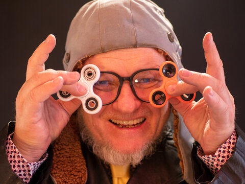elderly pensioner in pilot's hat, large glasses with gray beard in leather coat. bizarre people. Portrait of strange man who twists a spinner on his nose. Freaky senior citizen. bizarre men