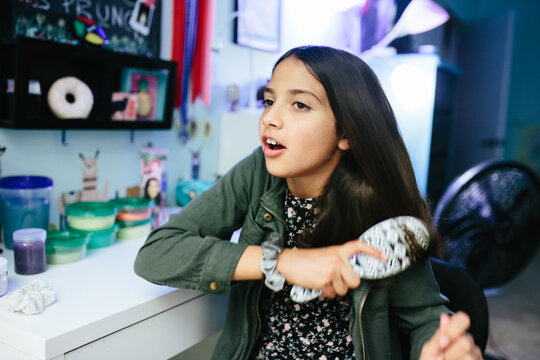 Tween girl brushing her hair in her bedroom