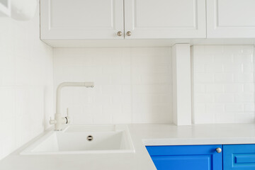 A modern bright kitchen with white and blue wardrobe.