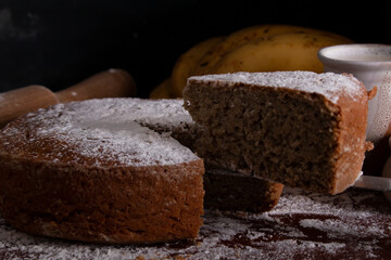 Fototapeta na wymiar Homemade banana or plantain cake portioned and portion of cake in a circular shape sprinkled with glass sugar flat front