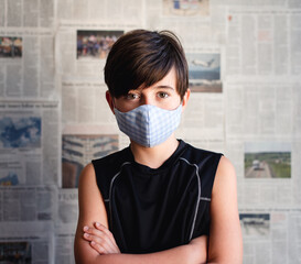 Boy wearing cloth mask against Covid 19 newspaper clippings.