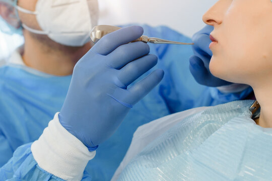 Close up hands of dental surgeon dentist holding dental tooth extraction tool and prepare for tooth extraction intervention.