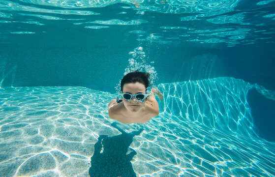 Underwater image of boy swimming in a pool with goggles on.