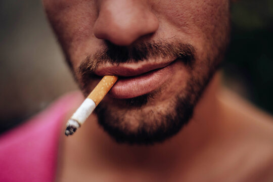 Mouth of a young man smiling while smoking a cigarette