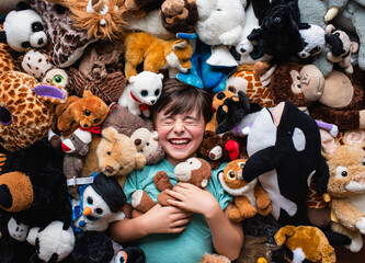 Happy young boy surrounded by his stuffed animals shot from above.