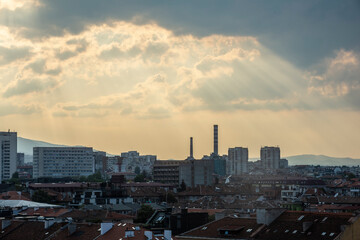 Radiating sun beams over Sofia with chimneys and roof