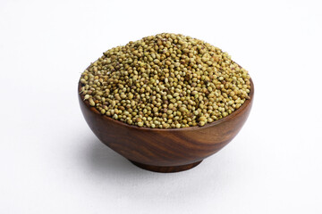 Fresh coriander seeds in wooden bowl and white background.