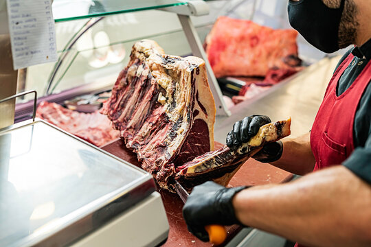 Professional butcher with mask preparing and cutting meat