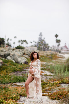 Young Pregnant Woman Posing at Beach in Sheer Dress