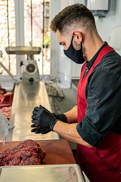 Butcher with mask Making raw beef burgers in butchers shop.