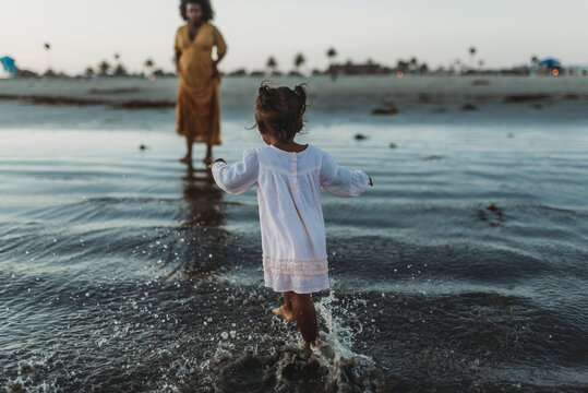 Young toddler girl splashing in the sea with family
