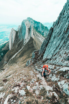 Elevated shot of young woman climbing up steep mountain face