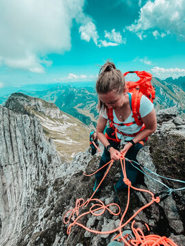 Young woman belaying climber on narrow ridge (Reitergrat) in Swiss alp