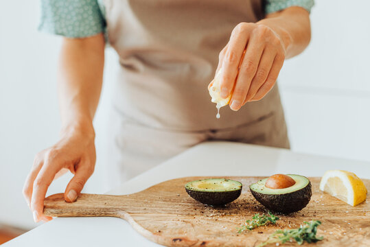 Close Up Of Female Hands Squeezing Lemon On Avocado