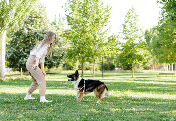 Couple playing with their dog in the park. Latino man and Caucasian woman with a Border collie