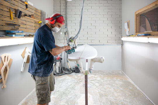 Surfboard shaper workshop - man checking quality of surfboard