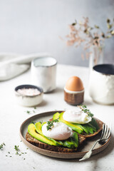 Healthy breakfast whole wheat toasted bread with avocado and poached egg over white background