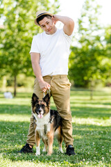 Obraz premium Young man walking his dog in the park. Latin model posing and watching on camera