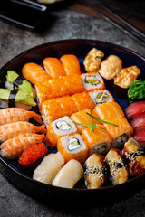 Set of sushi and maki with soy sauce over black background. Top view with copy space