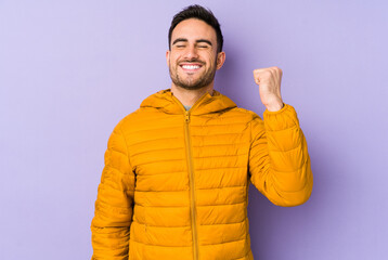 Young caucasian man isolated on purple background celebrating a victory, passion and enthusiasm,...