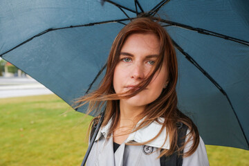 a young woman with red hair under a blue umbrella
