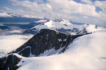 Photo of a glacier and ice fields amidst snow covered mountain peaks in Alaska