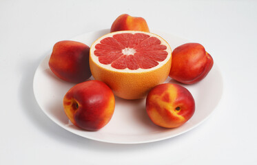 Fresh Red Grapefruits and nectarines on a plate. White background.