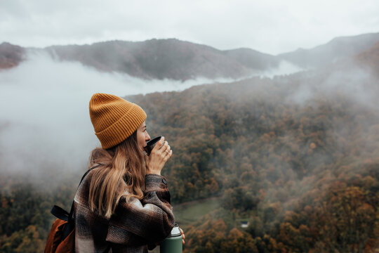 Portrait of woman traveling and exploring nature, preparing tea in a high place.