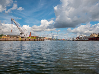 Lübeck port industrial area with cranes and massive clouds at the background