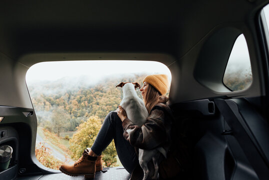 Portrait of a woman with her dog resting from a long trip in the trunk of her car.