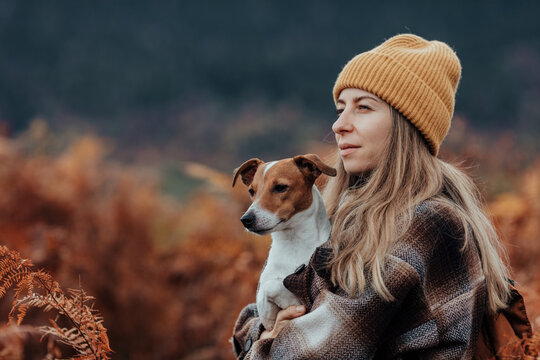 Portrait of a woman with her dog in a field of brown ferns, in autumn time.