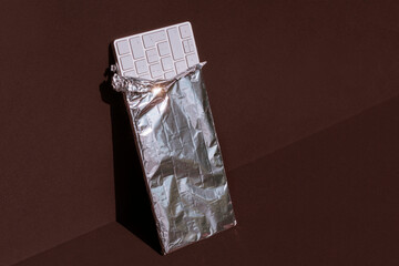 Keyboard as Fake White Chocolate Bar wrapped in a Silver Aluminium Kitchen Foil on a Brown Background . Technology Concept