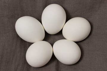 View of chicken eggs in shell on brown natural textile background.