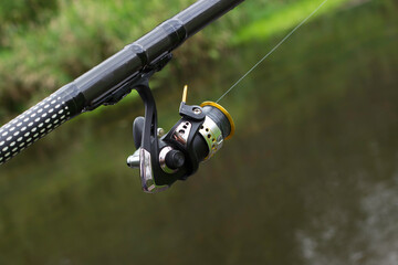 Fishing tackle. Reel on a fishing rod on the background of the river.
