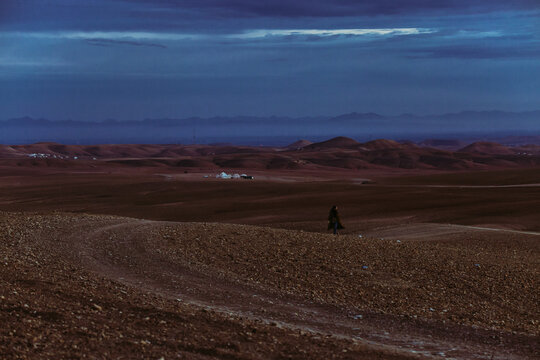Anonymous Woman Walking in Desert at Dawn