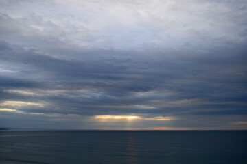 Dramatic and intense clouds over the sea with rays of sunset light