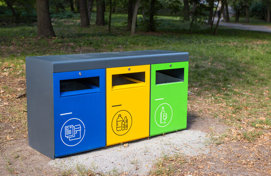 Three different garbage container for sorting waste in the park. Yellow for plastic, green for glass, blue for paper. Separating and sorting trash, concept pollution of the environment.