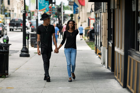 Holding Hands And Walking Down A City Sidewalk